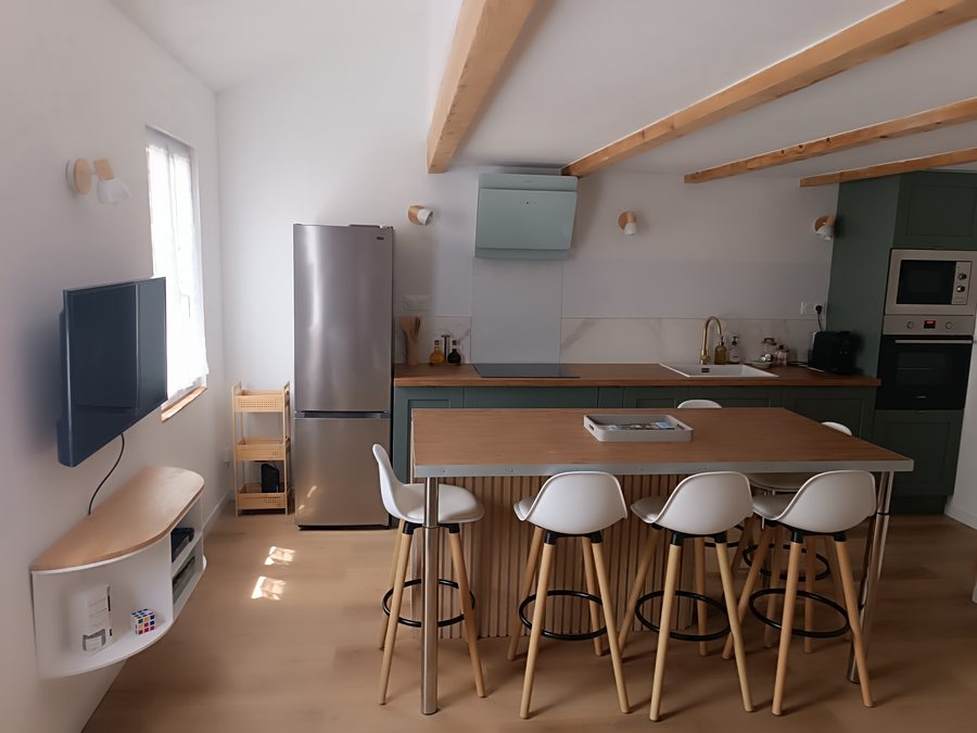 Salon-cuisine ouvert avec îlot en bois et poutres apparentes